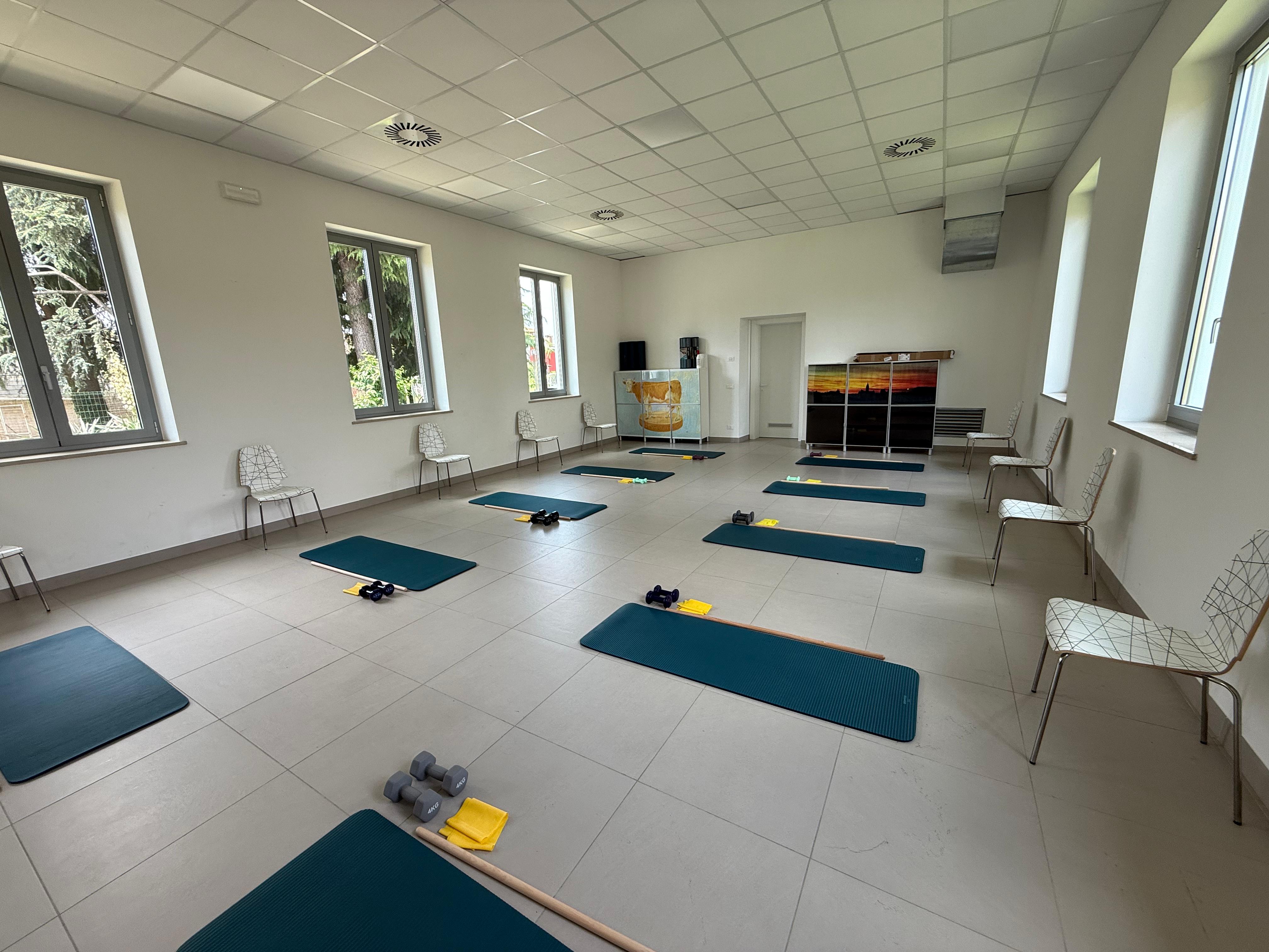 Sala allenamento funzionale con tappetini, pesi e bastoni per gli esercizi